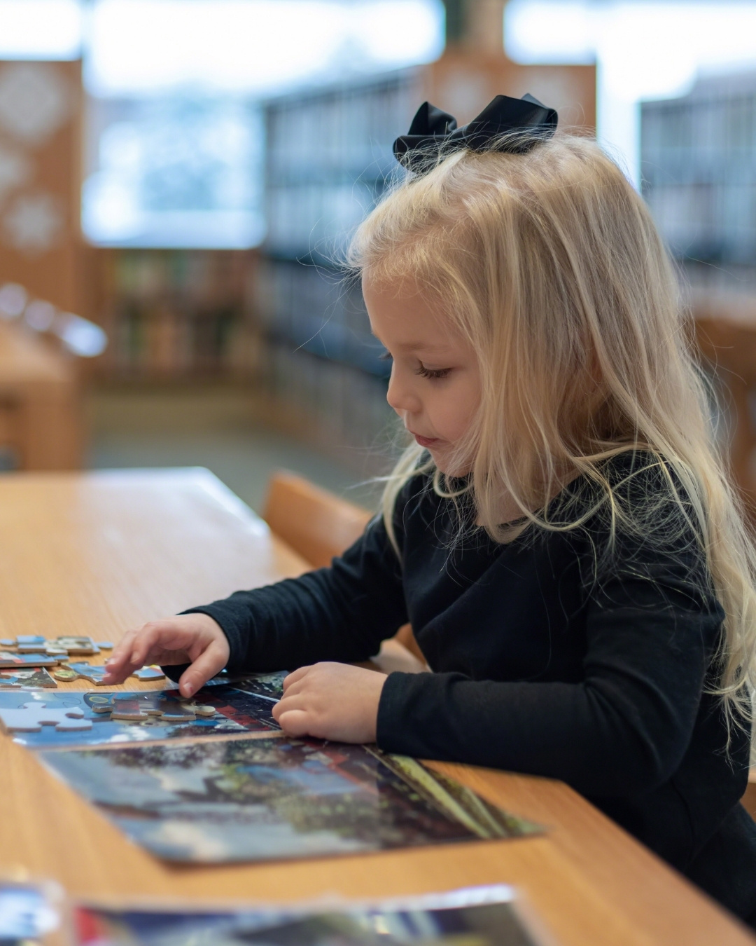 Little girl working on a puzzle in a library