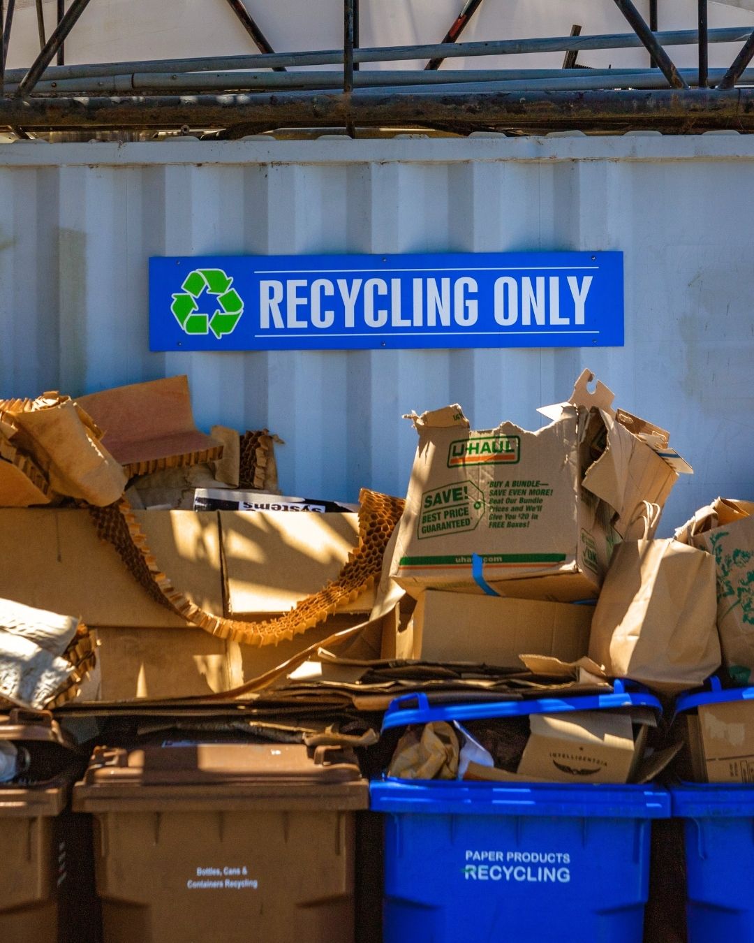 "Recycling Only" sign above bins overflowing with cardboard