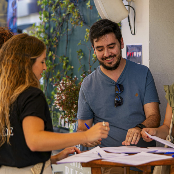 Two adults stand a small high-top table filling out paperwork